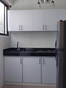内瓦Encantador y Confortable Apartamento的厨房配有白色橱柜、水槽和冰箱。
