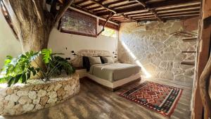 乌鲁瓦图Roots Tree House的卧室配有一张石墙床