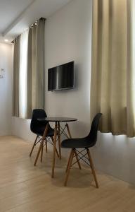 公主港Bambu Suites的两把椅子和一张桌子,墙上有电视