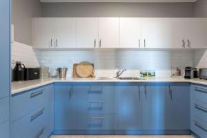 丹马克Belvoir - Denmark的蓝色的厨房,配有白色的橱柜和水槽