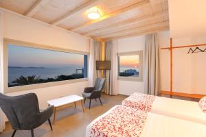 圣斯特凡诺斯O Lofos Luxury Boutique Suites的酒店客房设有一张床和一个大窗户