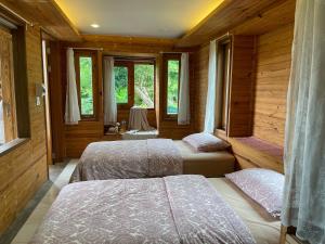 Ban Pa LauTime Pala-U Garden Villa (Noncee House)的配有木墙和窗户的客房内的两张床