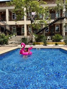 乔尔蓬阿塔Гостевой дом Асель的游泳池里一个粉红色木筏上的小女孩