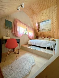 里加Amazing little house on an island with garden的一间卧室配有一张床、一张桌子和一把红色椅子