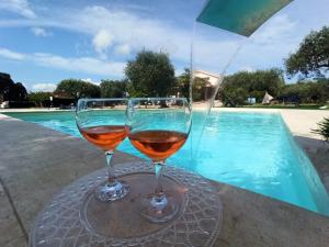 阿尔盖罗Villa Marianna的两杯酒坐在游泳池附近的桌子上
