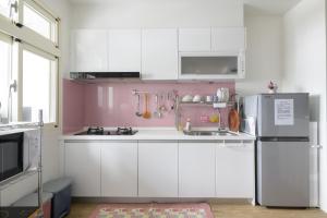 宜兰市乘風之旅溫馨包層華廈每日只接待一組客人最多6人的粉红色的厨房配有白色橱柜和冰箱