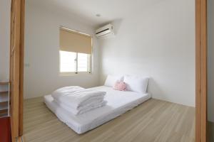 宜兰市乘風之旅溫馨包層華廈每日只接待一組客人最多6人的一间卧室配有带白色床单和粉红色枕头的床
