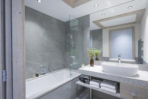 马尼戈Résidence Le Hameau de l'Ours的浴室配有盥洗盆、浴缸和盥洗盆