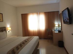 日惹阿朱酒店的一间设有大床和窗户的酒店客房