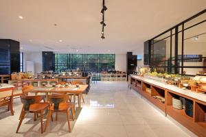 三宝垄Metro Park View Hotel Kota Lama Semarang的餐厅设有木桌、椅子和窗户。