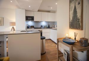 伦敦Kensington High Street One Bed的厨房配有白色橱柜和木桌