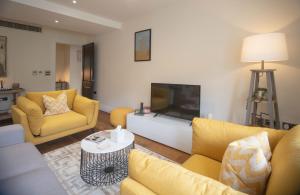 伦敦Kensington High Street One Bed的客厅配有黄色家具和平面电视
