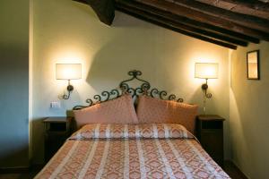 Civitella Marittima甲板住宿加早餐旅馆的卧室配有一张床,墙上挂着两盏灯