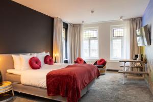法尔肯堡Dormio Wijnhotel Valkenburg的酒店客房配有一张带红色枕头的大床