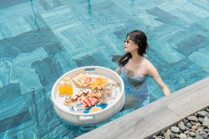 岘港Seahorse Tropical Da Nang Hotel by Haviland的游泳池里的女人,吃一碗食物
