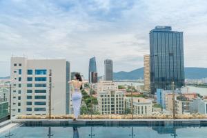 岘港Seahorse Tropical Da Nang Hotel by Haviland的站在一座俯瞰城市的建筑边缘的女人