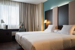 潘普洛纳AZZ Pamplona Norte Hotel的酒店客房设有一张大床和一张书桌。