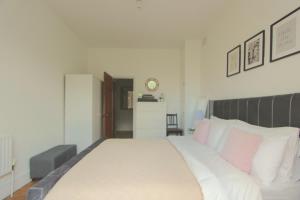 伦敦Beautiful one bed garden flat in Muswell hill的卧室配有带粉红色枕头的大型白色床