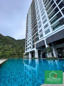 淡文Ojies Home Sunway Onsen Suites 2BR Theme Park View的一座大型建筑,前面设有一个游泳池