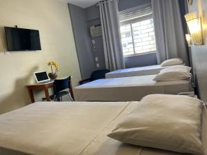 巴西利亚里维埃拉酒店的酒店客房设有三张床和一张位于书桌上的笔记本电脑