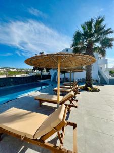梅萨雷亚Santorini Villatzio Suites的一排带遮阳伞和游泳池的躺椅