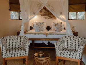 侯斯普瑞特Nyala Safari Lodge的卧室配有白色的床和两把椅子
