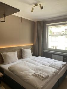 杜塞尔多夫Hotel Petite Königsallee SELF CHECK-IN的一间卧室配有一张带白色床单的床和一扇窗户。