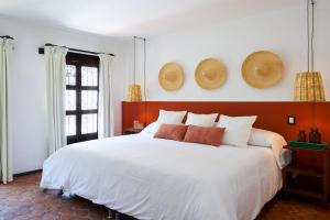 墨西哥城AmazINN Places Casa Coyoacan的卧室配有一张白色大床,墙上挂有帽子