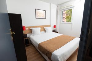 里昂Apparthotel Privilodges Lyon Lumière的一间卧室配有一张带白色床单的床和一扇窗户。