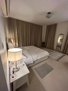 阿卜杜勒国王经济城شقة الاحلام的一间卧室配有一张床和一张带台灯的桌子