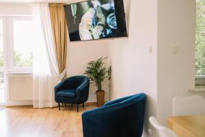 克拉科夫Girls Willa的客厅配有两把椅子和墙上的电视