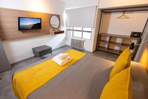 圣卡洛斯-德巴里洛切HOTEL CONCEPT BARILOCHE的一间卧室配有黄色的床和电视