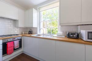 伦敦Charming & Central 2BD Flat - Islington的厨房配有白色橱柜、水槽和窗户。