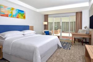 马卡萨望加锡福朋喜来登酒店的卧室配有一张白色大床和一张书桌