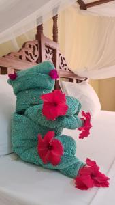 肯杜瓦Villa Vanilla Kendwa的床上的绿色毛巾,红色鲜花