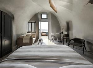 易莫洛林Kivotos Santorini的卧室配有一张床和一张桌子及椅子