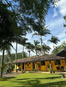 林多亚Pousada Recanto dos Pássaros的棕榈树前方的黄色房子