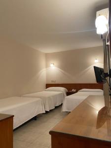 瓦伦西亚Hostal Blayet的带3张白色床单的床的房间