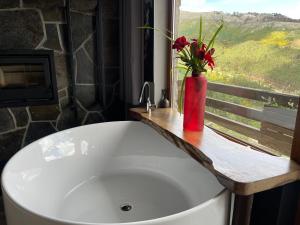 维拉·雷阿尔Muas Guest House的浴室内设有一个白色浴缸,花瓶装有花卉