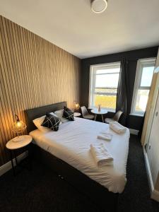 伊斯特布恩OYO Marine Parade Hotel, Eastbourne Pier的一间卧室配有一张带两张桌子和两个窗户的床。