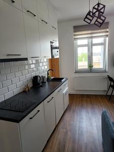 格丁尼亚蓝调客房旅舍的厨房配有白色橱柜和黑色台面