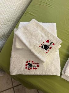 布林迪西Archome Luxury Apartment的两条白色毛巾,坐在绿床的顶部