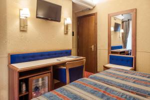 米兰德斯艾特昂格尔斯酒店的客房设有一张床、一张书桌和一面镜子