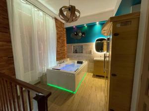 ChartrettesSuite d'amour et détente jacuzzi, sauna et massage的带浴缸和绿色照明的大浴室