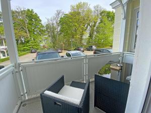 奥斯特巴德·哥伦Villa Strandmuschel - FeWo 01的阳台配有椅子,享有停车场的景致