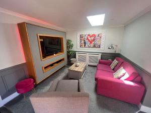斯凯格内斯Luxury 5* Woodland Retreat, In The Woods.的客厅配有粉红色的沙发和电视
