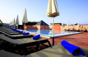 洛斯克里斯蒂亚诺斯Hotel Reveron Plaza的一个带蓝色躺椅和遮阳伞的游泳池