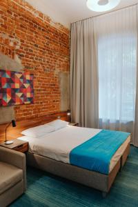 罗兹托巴克罗兹酒店的一间卧室设有一张床和砖墙