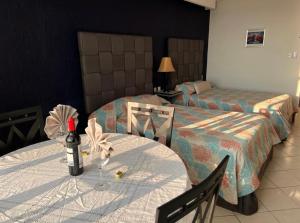 坎昆Solymar Condos的酒店客房设有两张床,桌子上放有一瓶葡萄酒