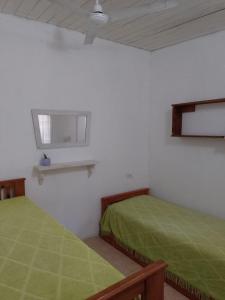 富内斯El séptimo día, lugar de descanso的白色客房的两张床,配有绿色床单